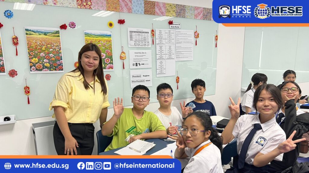 A teacher smiling and posing for a group photo with her class of students.