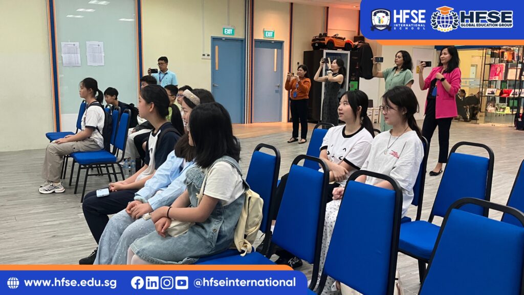 A group of students seated on blue chairs.