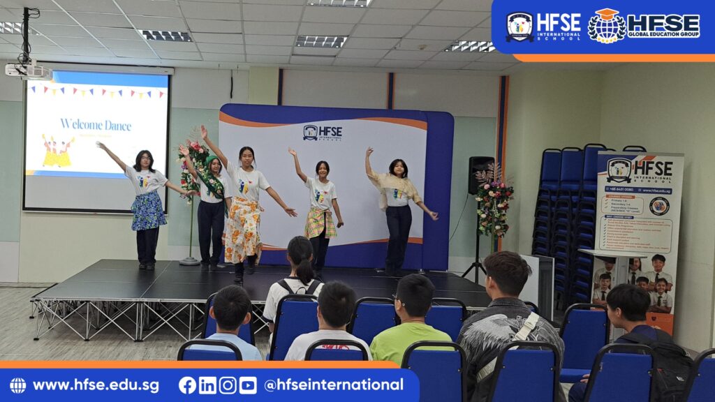 A group of students performing a dance on stage in front of their schoolmates.