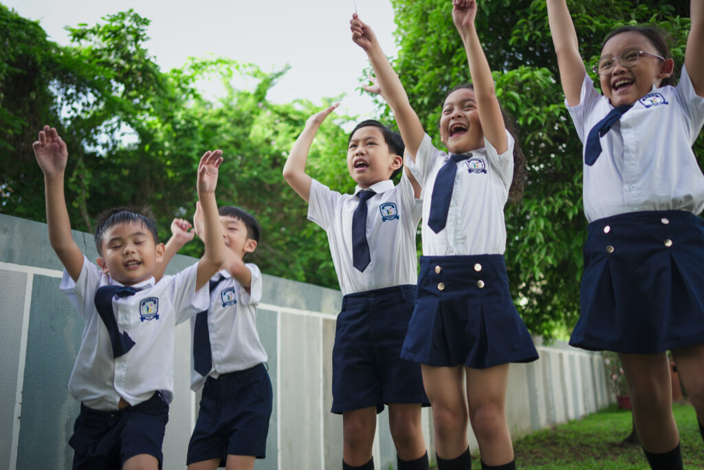 HFSE International School Primary students in Singapore having fun outside, jumping with glee.
